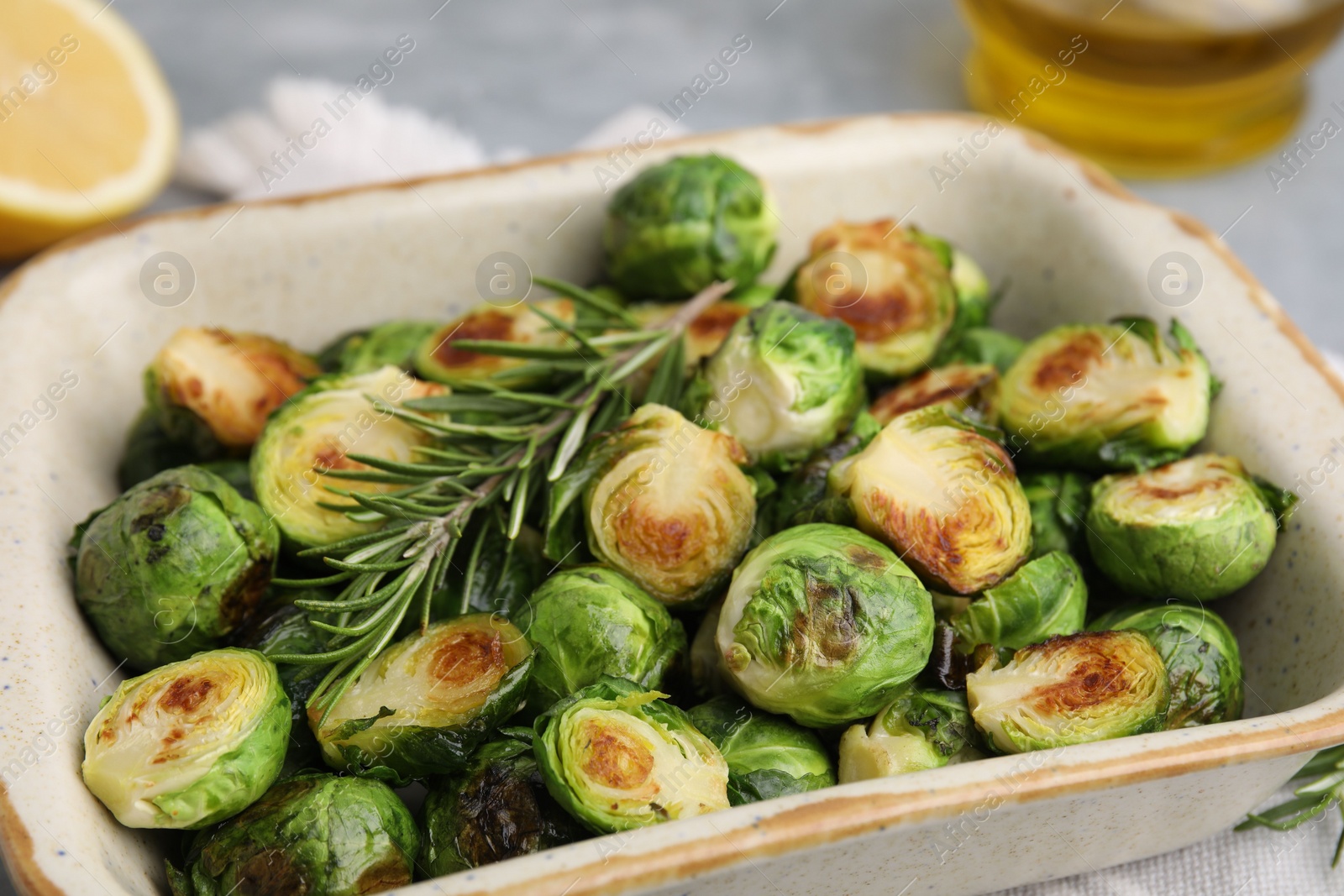 Photo of Delicious roasted Brussels sprouts and rosemary in baking dish on table, closeup