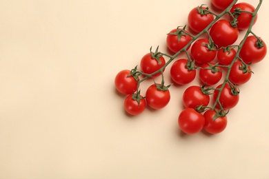 Branches with fresh cherry tomatoes on beige background, flat lay. Space for text