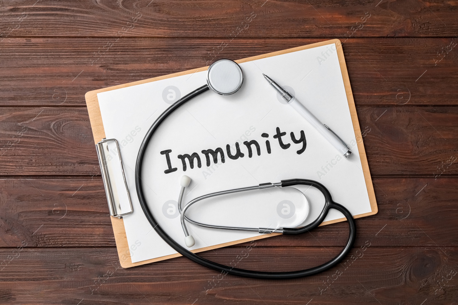 Photo of Clipboard with word Immunity and stethoscope on wooden table, top view