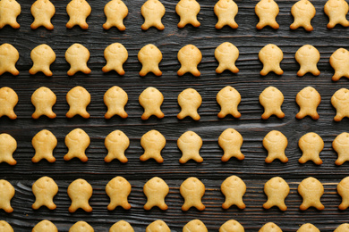 Delicious goldfish crackers on black wooden table, flat lay