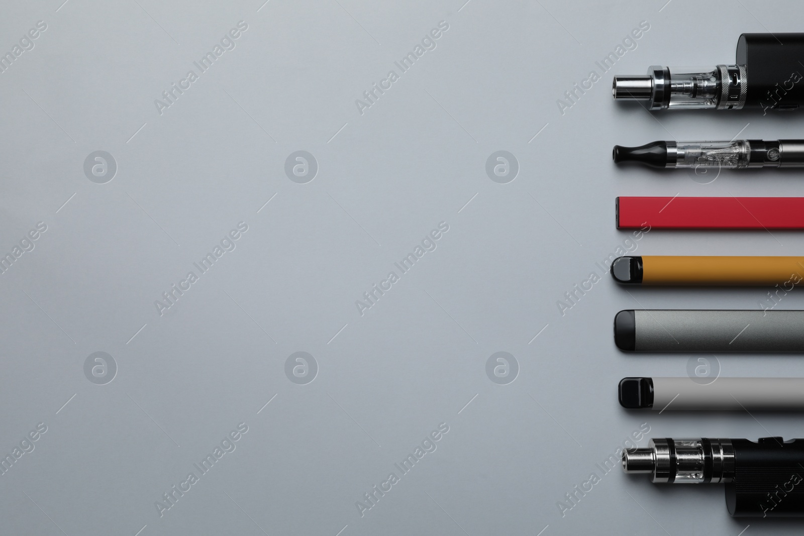 Photo of Many different electronic cigarettes on light background, flat lay. Space for text