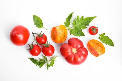 Many different ripe tomatoes and leaves on white background, flat lay