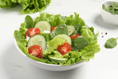 Delicious salad in bowl on white table, closeup
