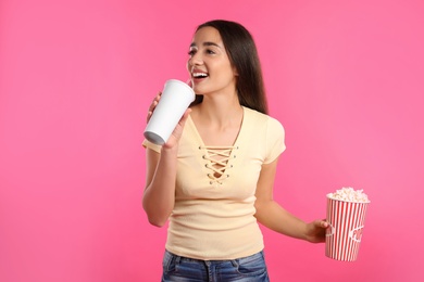 Woman with popcorn and beverage during cinema show on color background