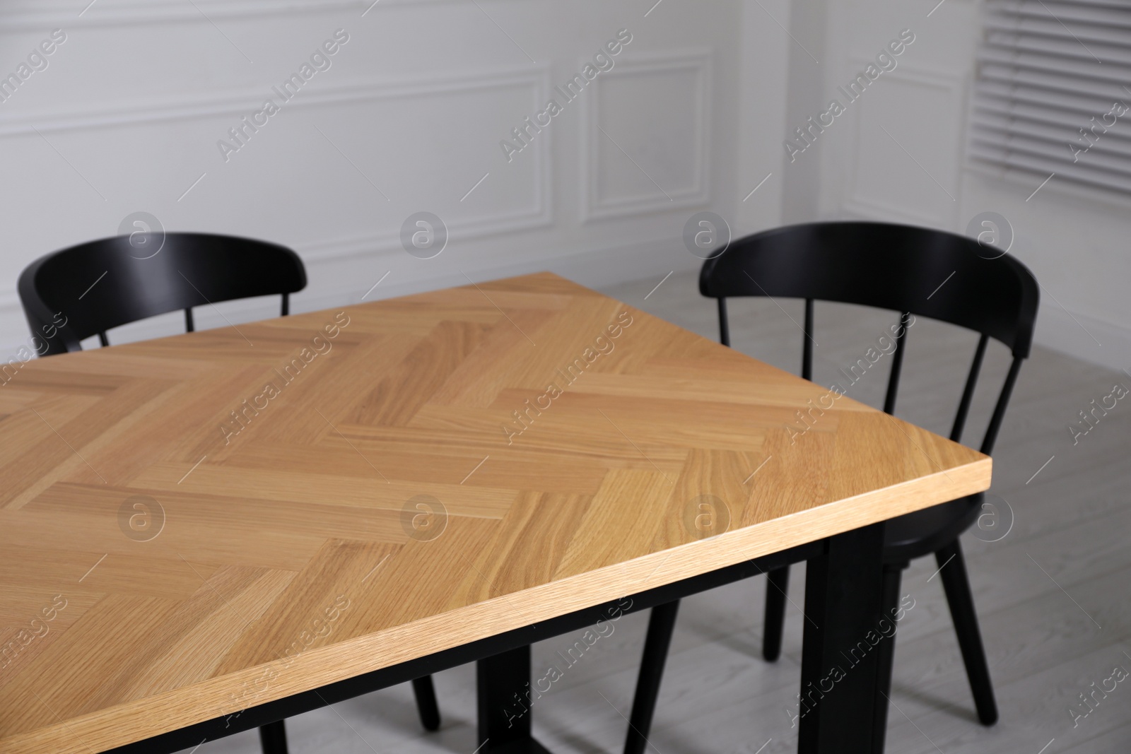 Photo of Wooden table and black chairs in room. Interior design