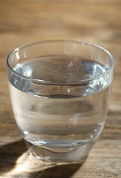 Glass of water on wooden table, closeup. Refreshing drink