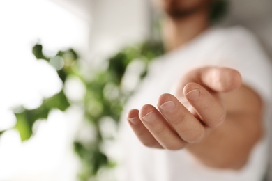 Photo of Man offering helping hand on blurred background, closeup. Space for text