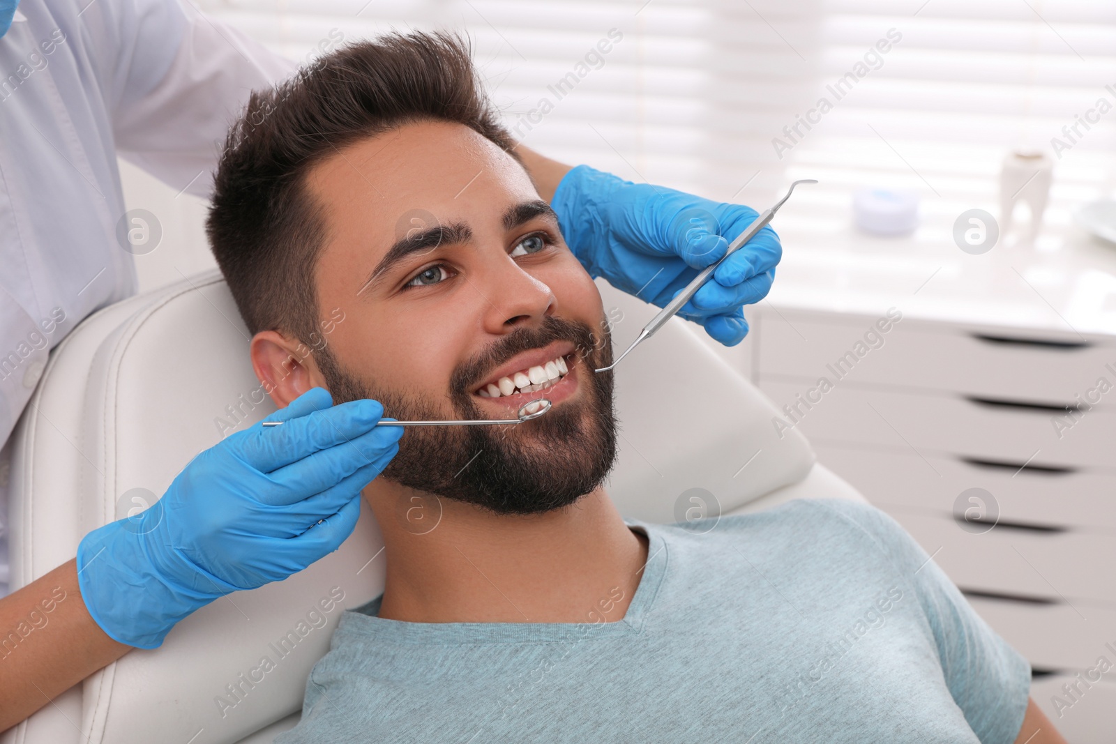 Photo of Dentist examining young man's teeth in modern clinic