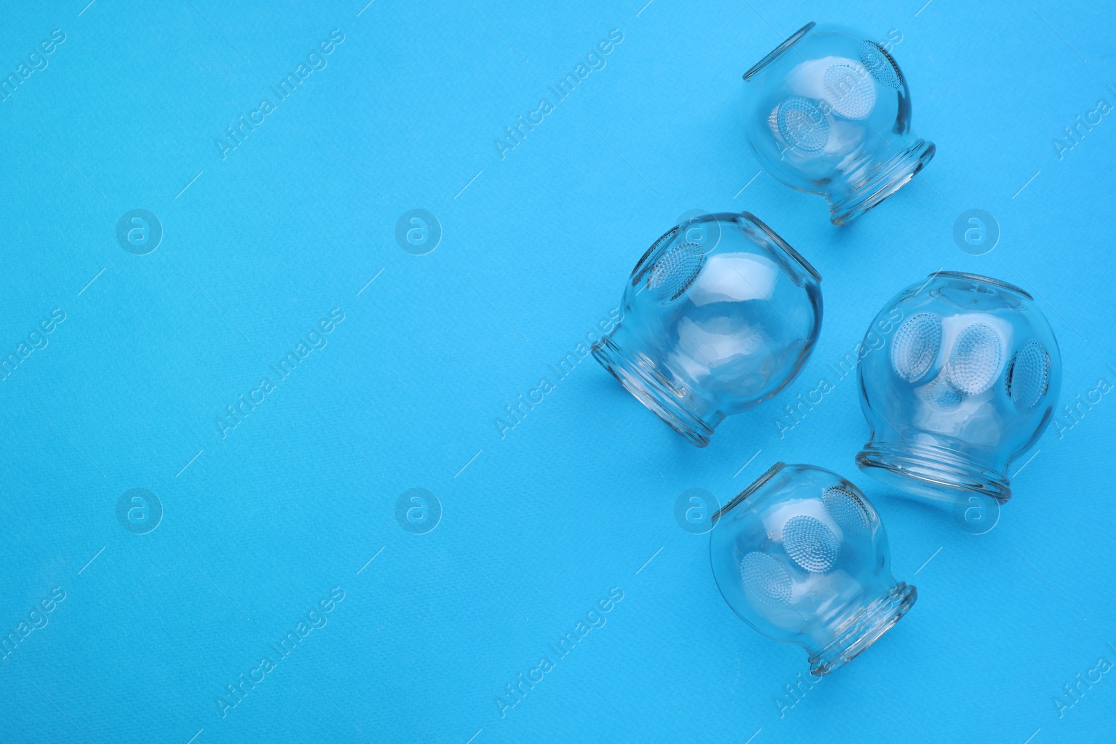 Photo of Glass cups on light blue background, flat lay and space for text. Cupping therapy