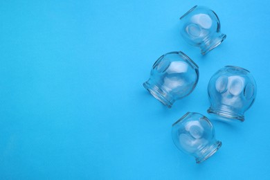 Photo of Glass cups on light blue background, flat lay and space for text. Cupping therapy