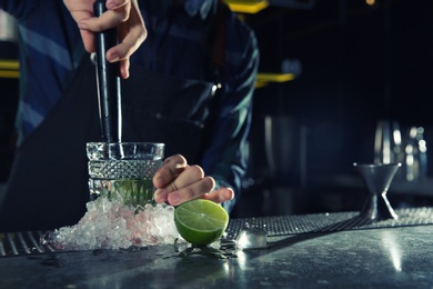 Barman making Mojito cocktail at counter in pub, closeup. Space for text