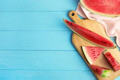 Photo of Yummy cut watermelon on light blue wooden table, flat lay. Space for text