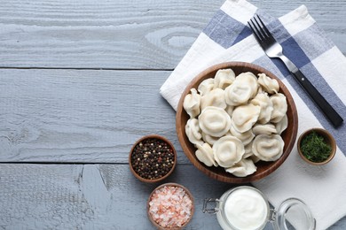 Tasty dumplings in bowl served on grey wooden table, flat lay. Space for text