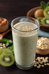 Photo of Glass of tasty kiwi smoothie with oatmeal on wooden table