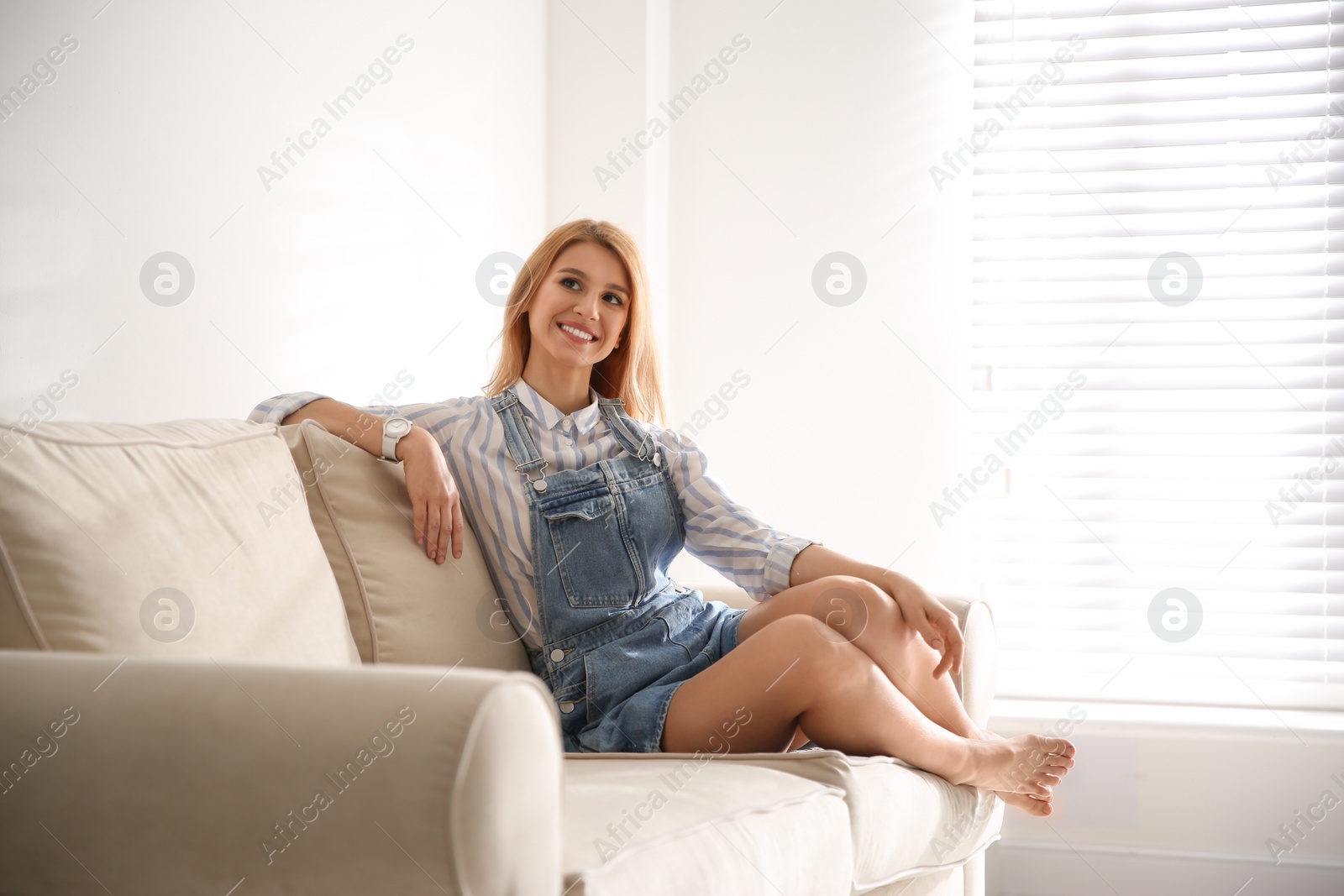 Photo of Young woman relaxing on couch near window at home