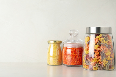 Photo of Glass jars with different types of groats on white wooden table