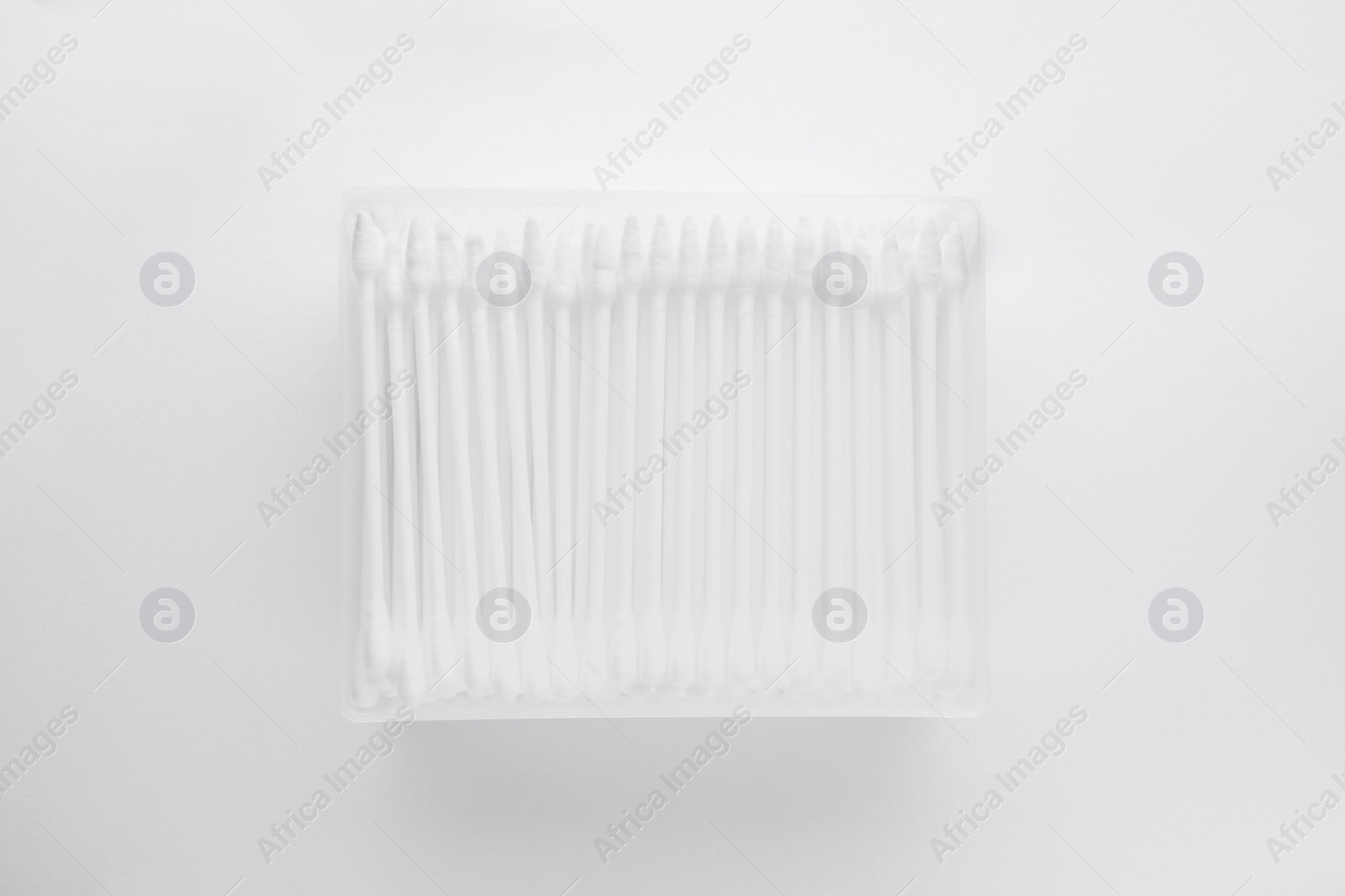 Photo of Cotton buds in plastic container isolated on white, top view