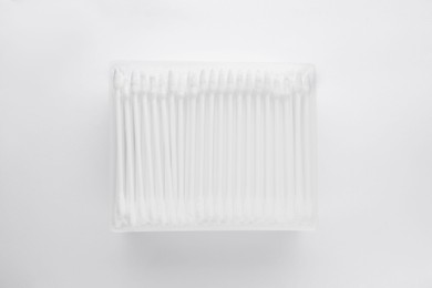 Photo of Cotton buds in plastic container isolated on white, top view