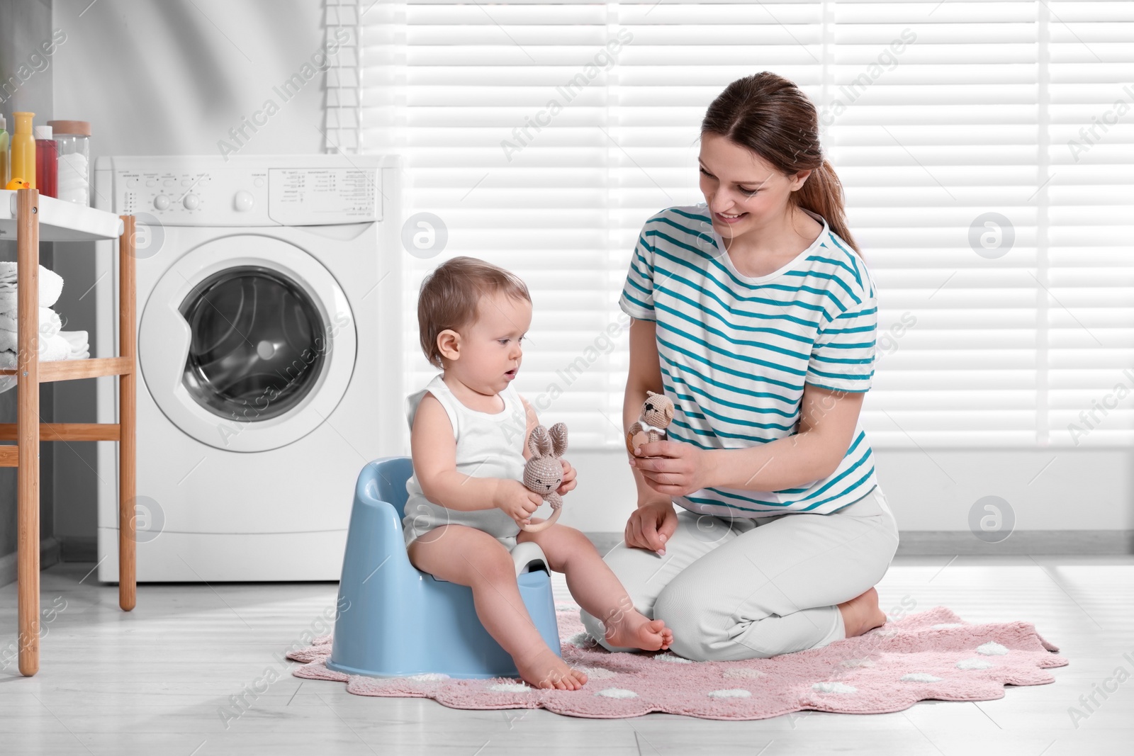 Photo of Mother training her child to sit on baby potty indoors