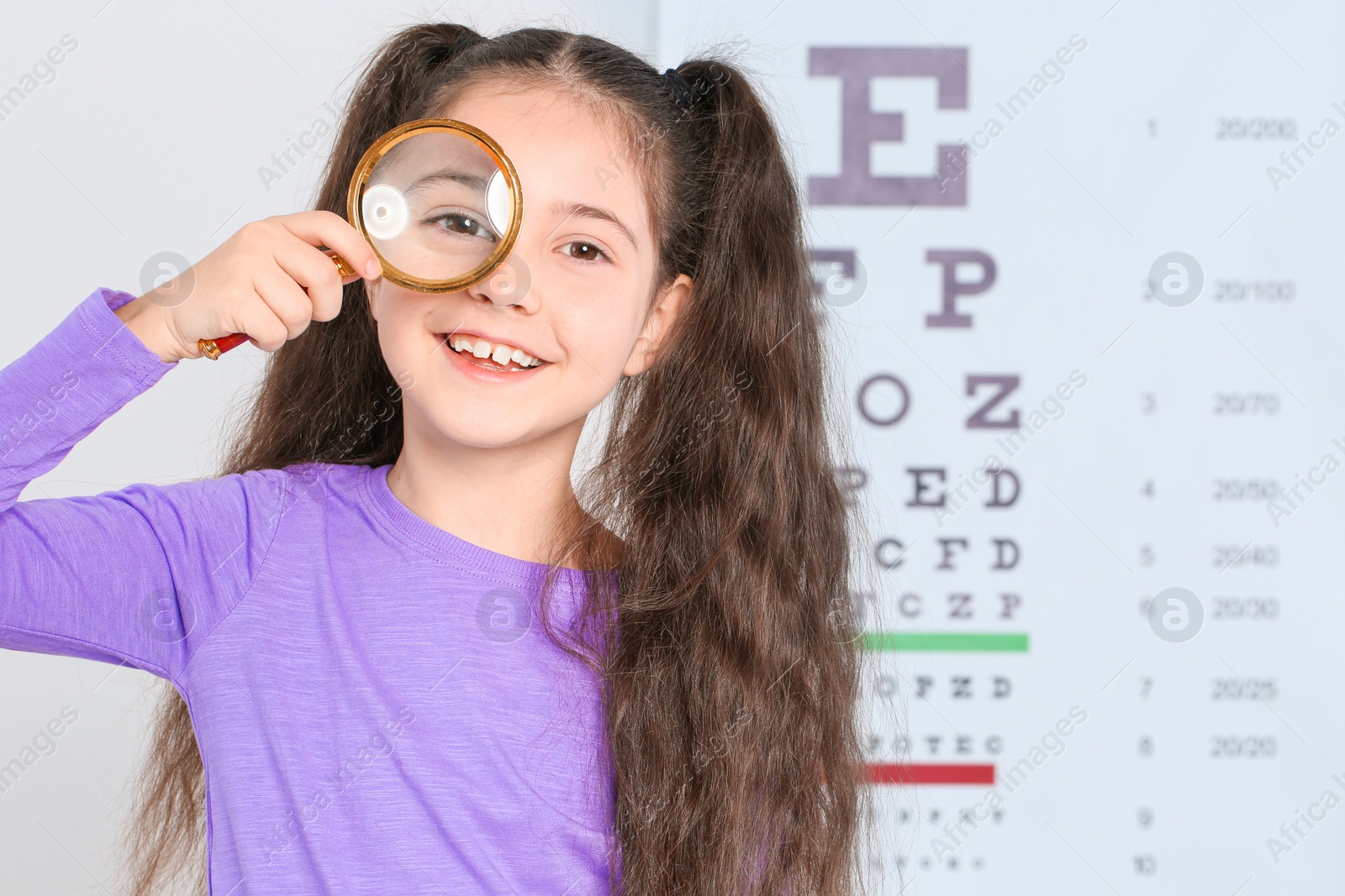 Photo of Little girl with magnifier visiting children's doctor, space for text. Eye examination