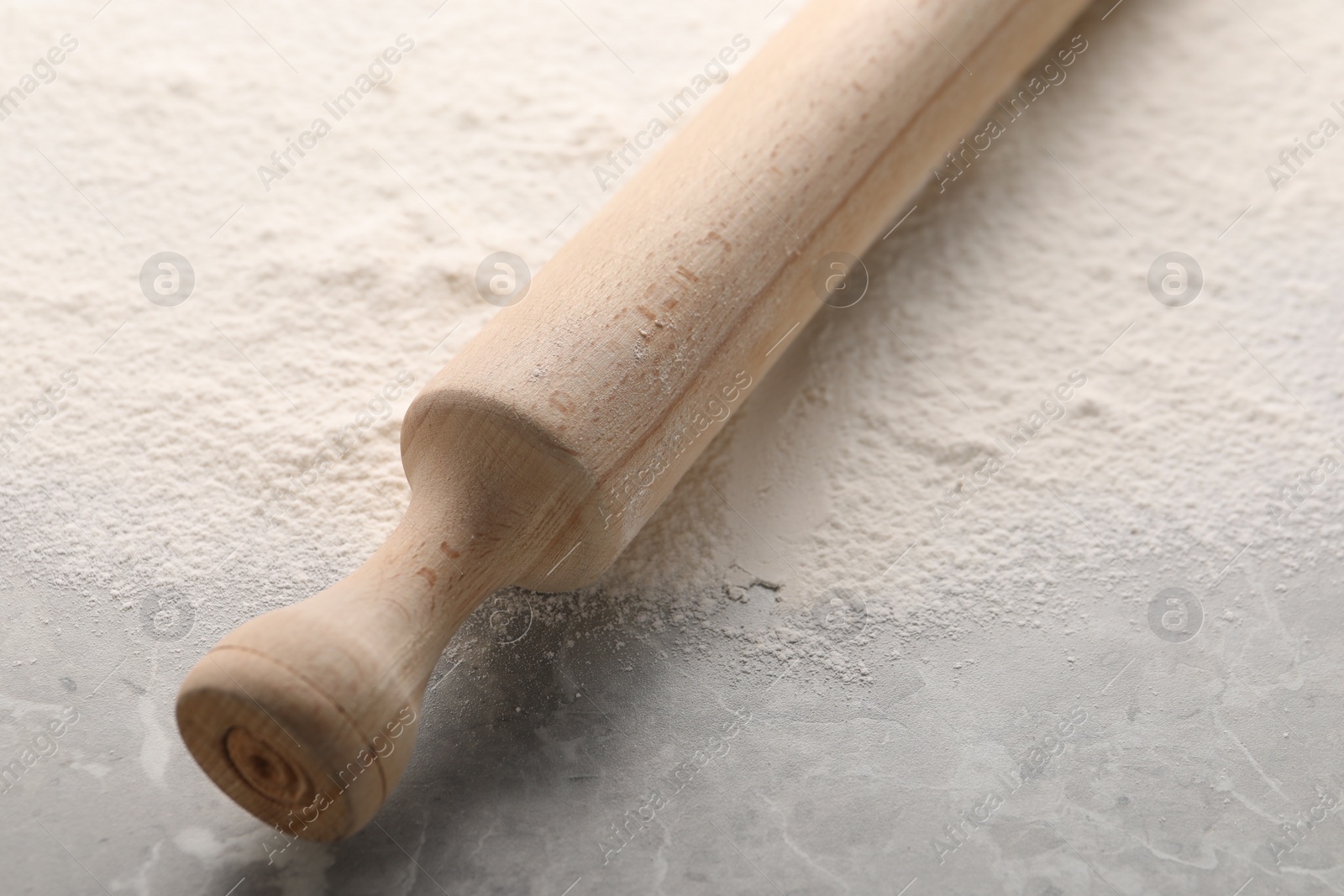 Photo of Rolling pin and flour on grey marble table, closeup