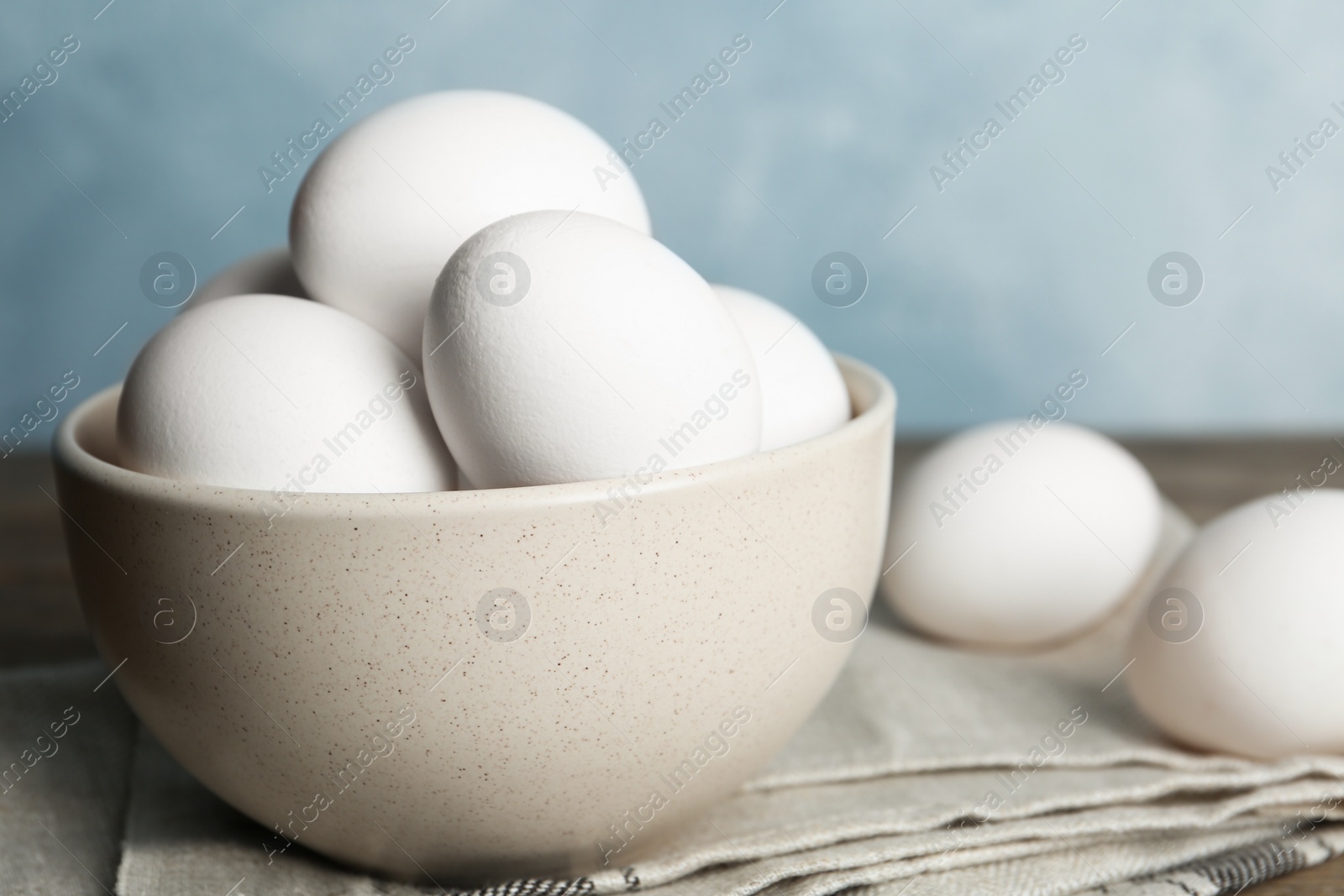 Photo of Many fresh raw chicken eggs in bowl on table, closeup