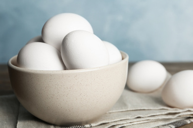 Photo of Many fresh raw chicken eggs in bowl on table, closeup