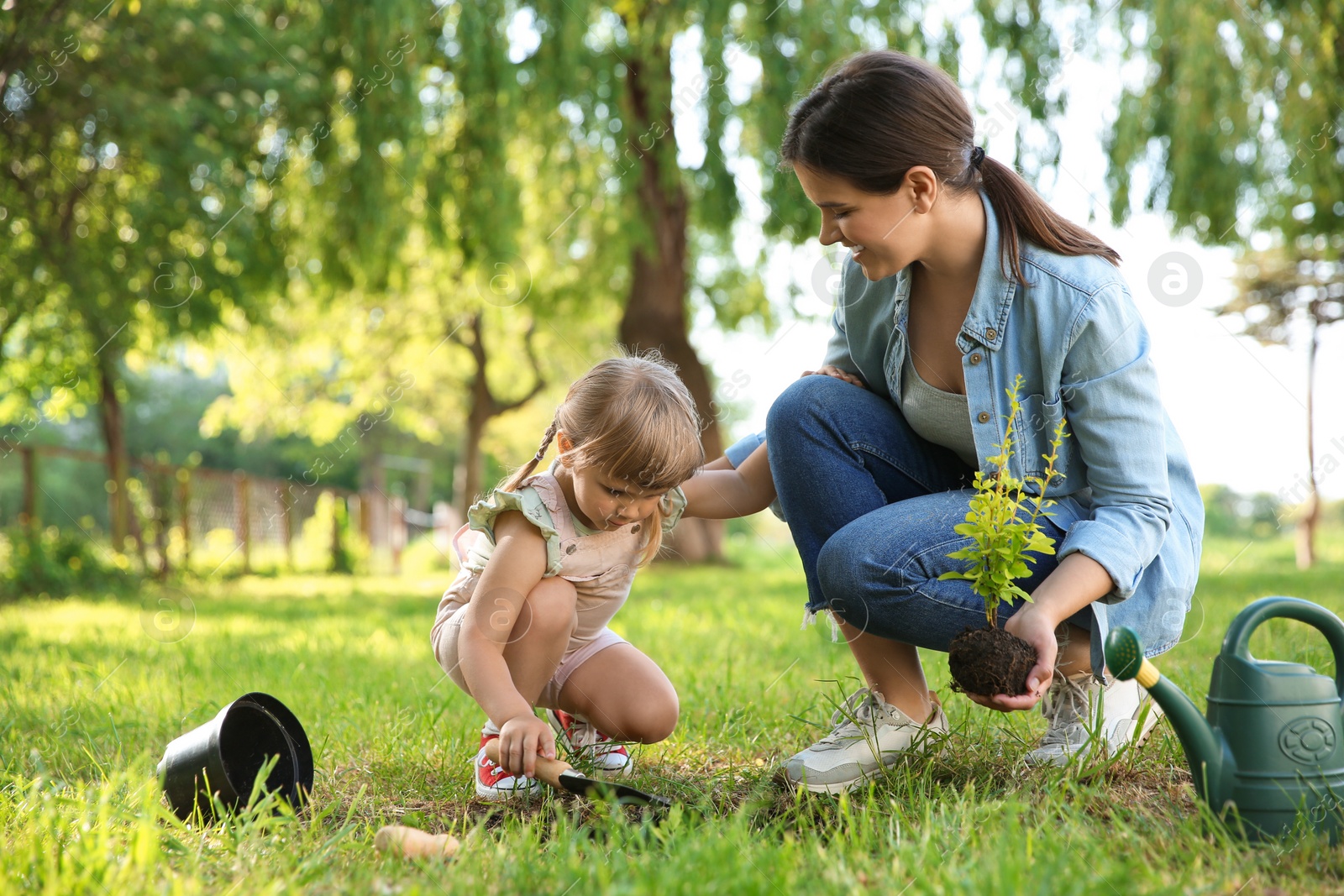 Photo of Mother and her daughter planting tree together in garden