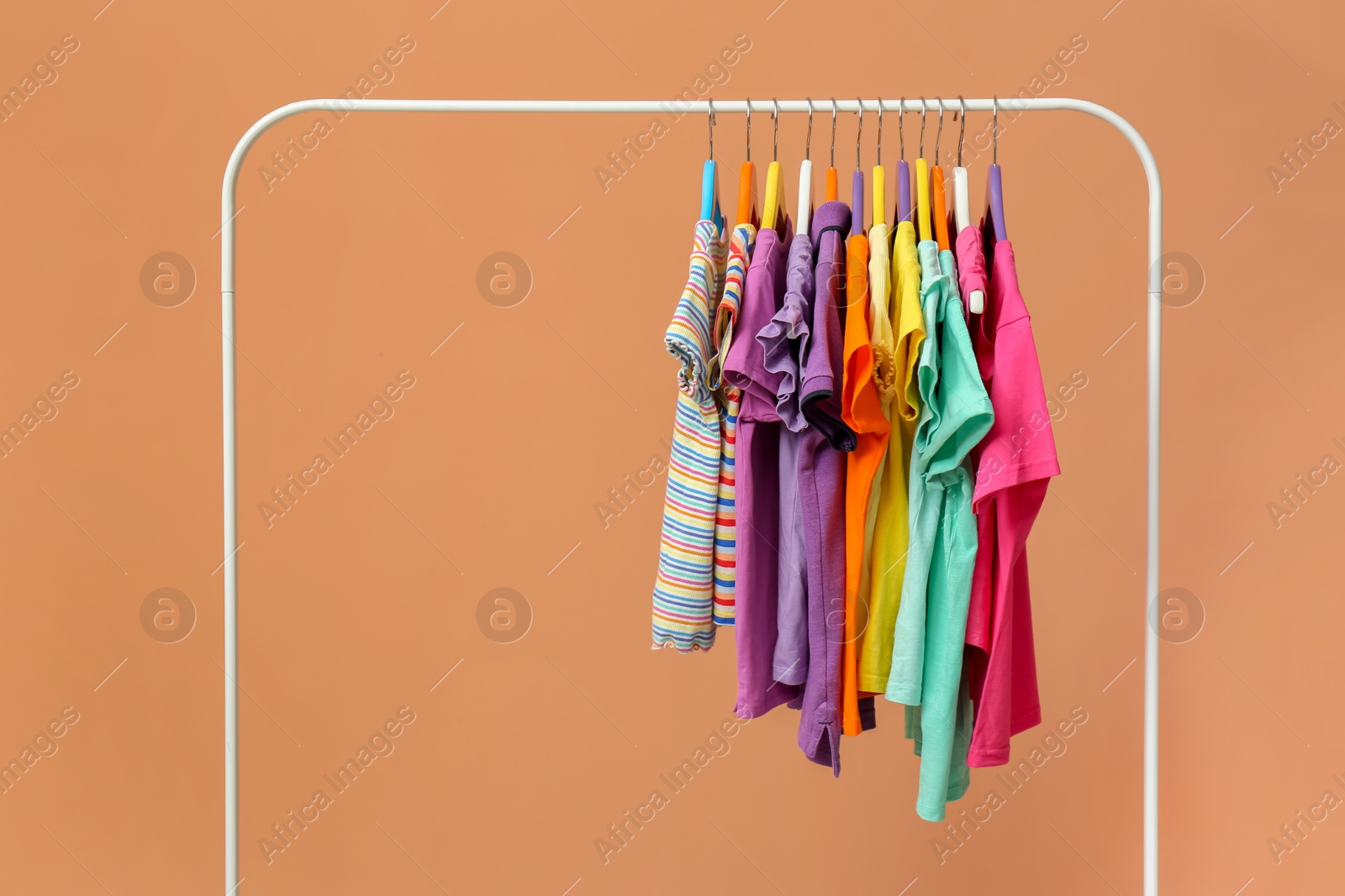 Photo of Rack with stylish children clothes on beige background