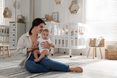 Photo of Happy young mother with her baby in nursery. Space for text