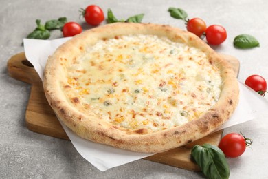 Delicious cheese pizza, basil and tomatoes on light grey table