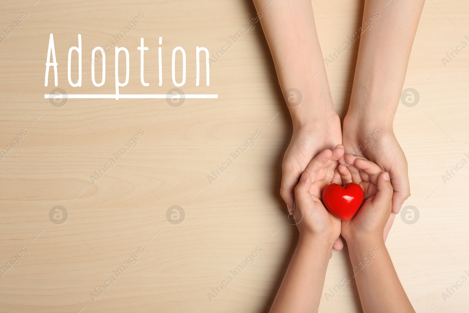 Image of Woman and child holding heart on beige wooden background, top view. Adoption concept