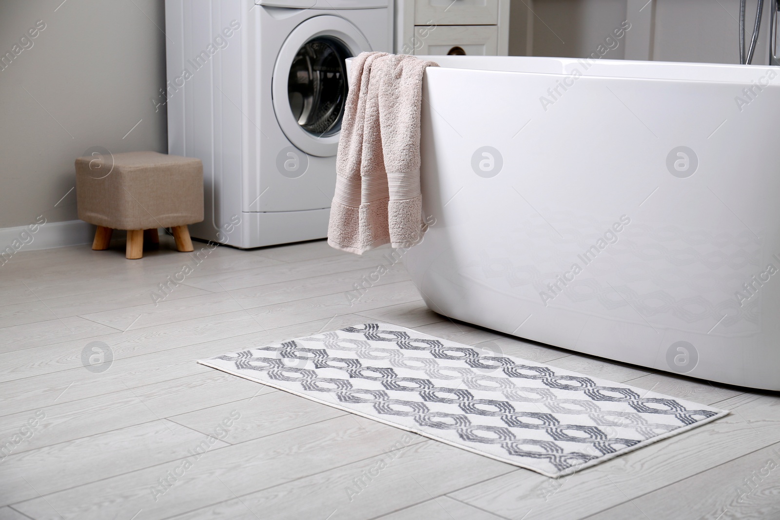 Photo of Stylish mat on floor near tub in bathroom. Interior design