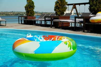 Colorful inflatable ring floating in swimming pool on sunny day, outdoors