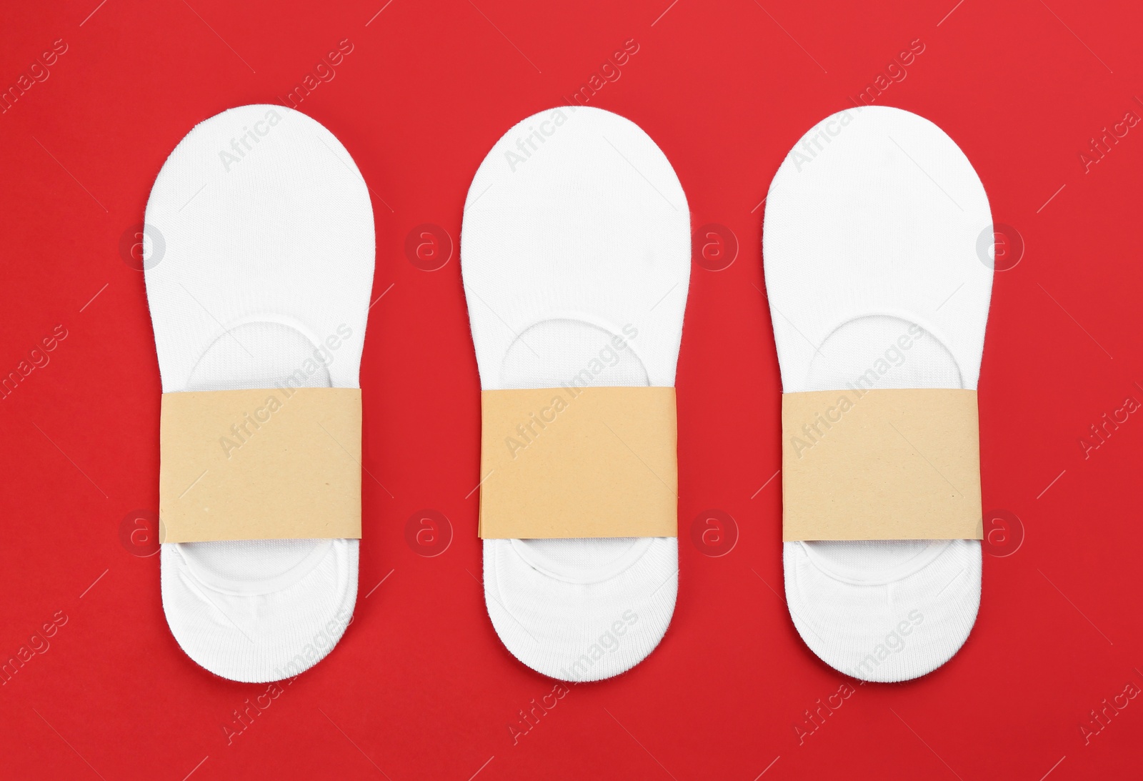 Photo of White cotton socks on red background, flat lay