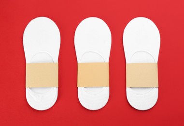 Photo of White cotton socks on red background, flat lay