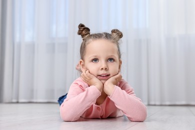 Photo of Cute little girl lying on warm floor at home. Heating system