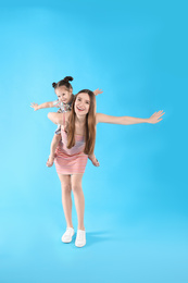 Photo of Young mother and little daughter having fun on light blue background