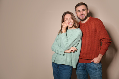 Lovely couple in warm sweaters on beige background. Space for text