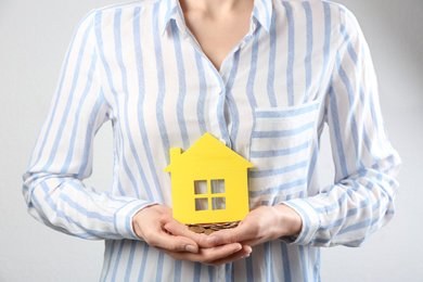 Photo of Woman holding coins and house model, closeup