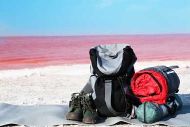 Photo of Set of camping equipment with sleeping bag on coast of pink lake