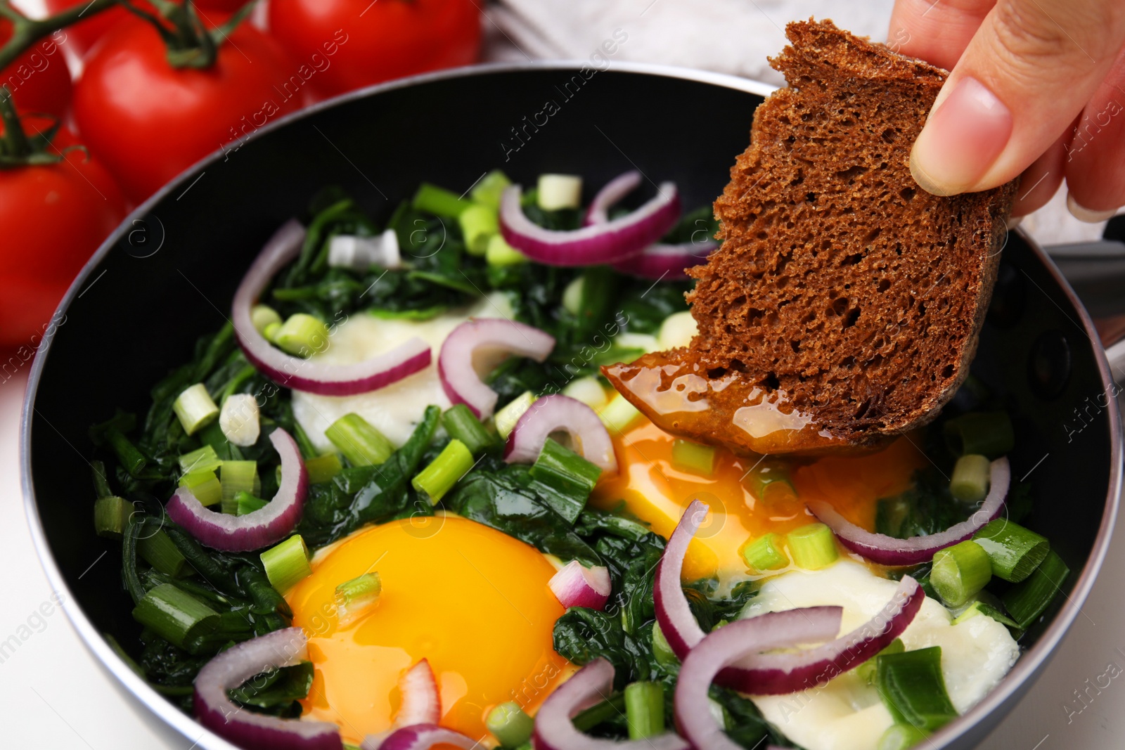 Photo of Woman dipping piece of bread into egg yolk, closeup. Eating tasty Shakshuka