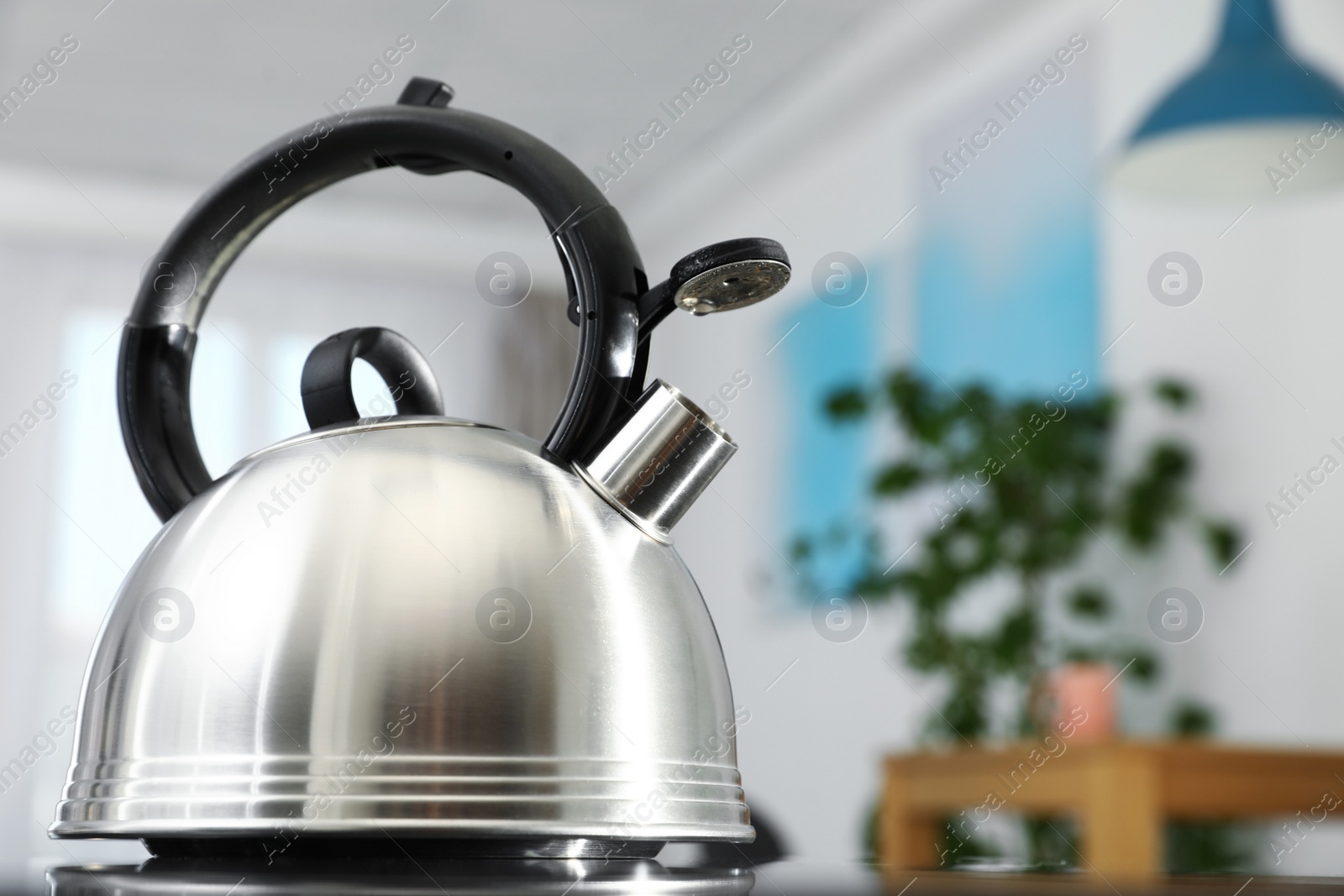 Photo of Modern kettle with whistle on stove in kitchen, space for text