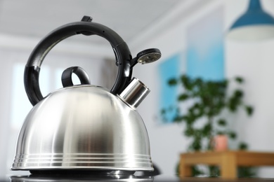 Photo of Modern kettle with whistle on stove in kitchen, space for text