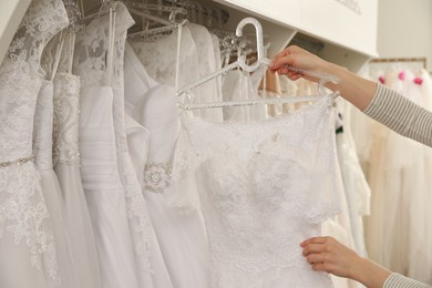 Photo of Young woman choosing wedding dress in salon, closeup