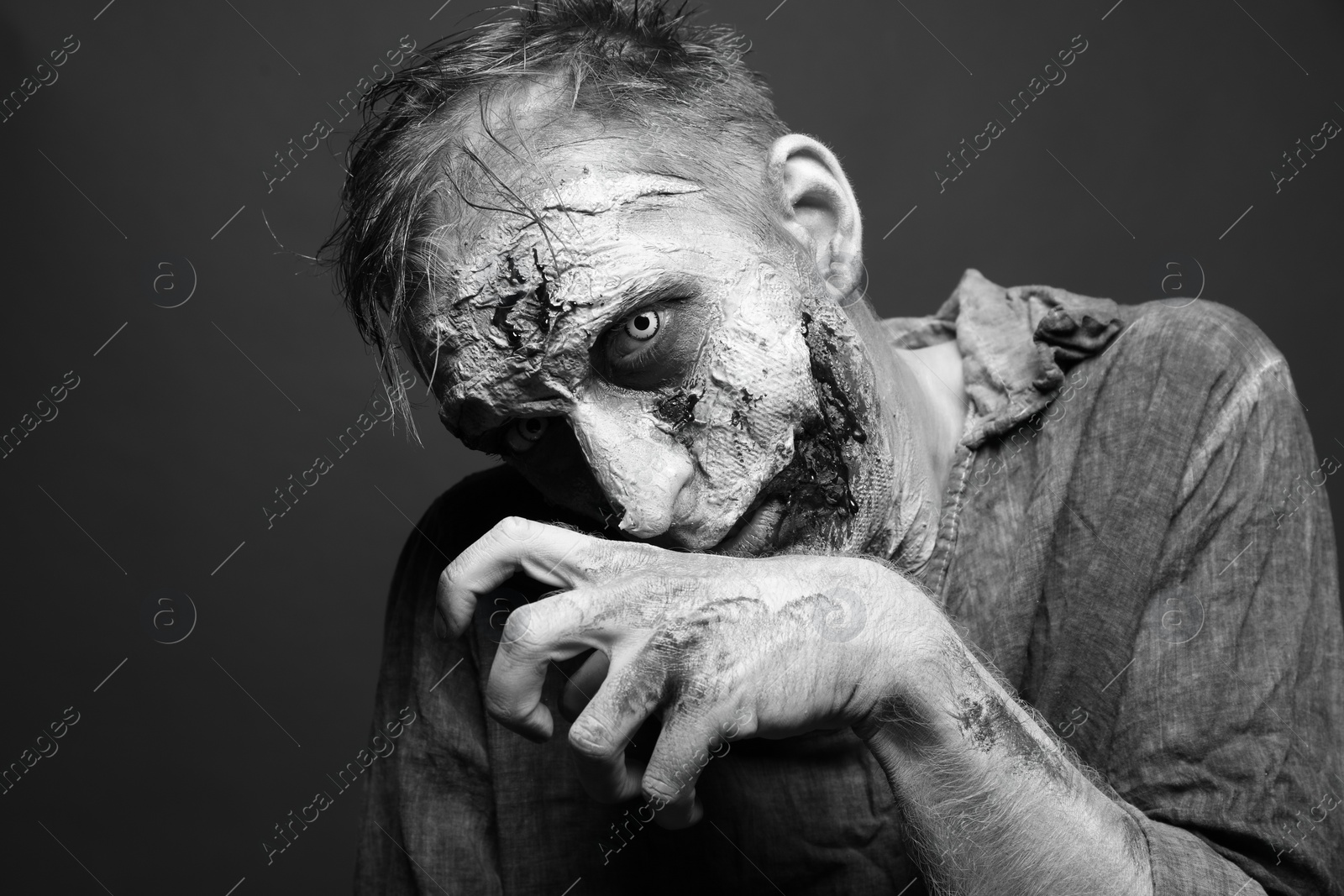 Photo of Scary zombie on dark background, black and white effect. Halloween monster