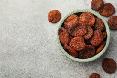 Photo of Bowl with tasty apricots on grey table, flat lay and space for text. Dried fruits