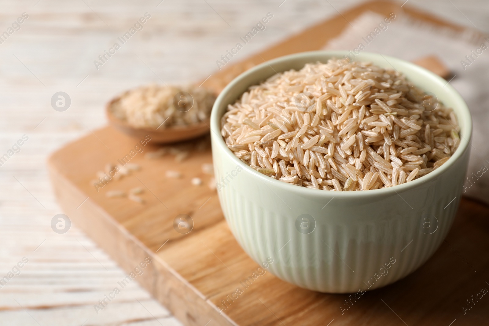 Photo of Uncooked brown rice in small bowl on table. Space for text