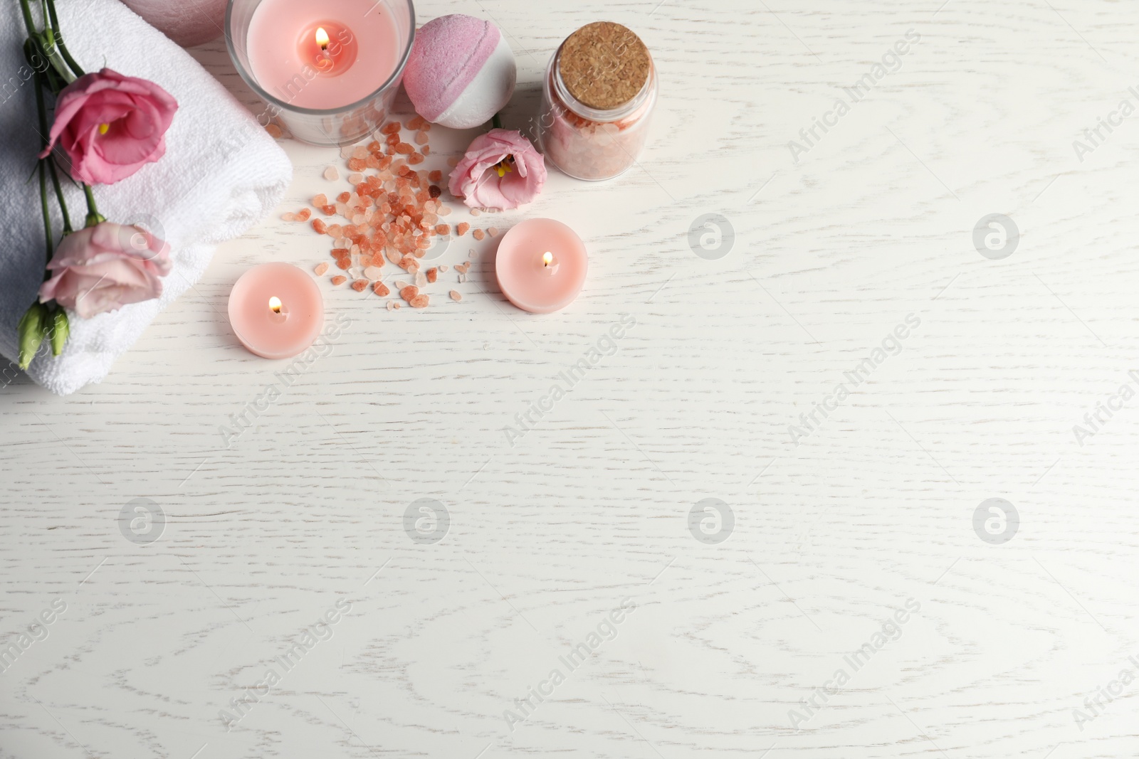 Photo of Flat lay composition with burning candles and different spa products on white wooden table. Space for text