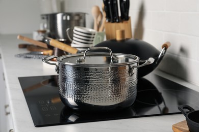 Photo of Metal pot and wok on cooktop in kitchen. Cooking utensils